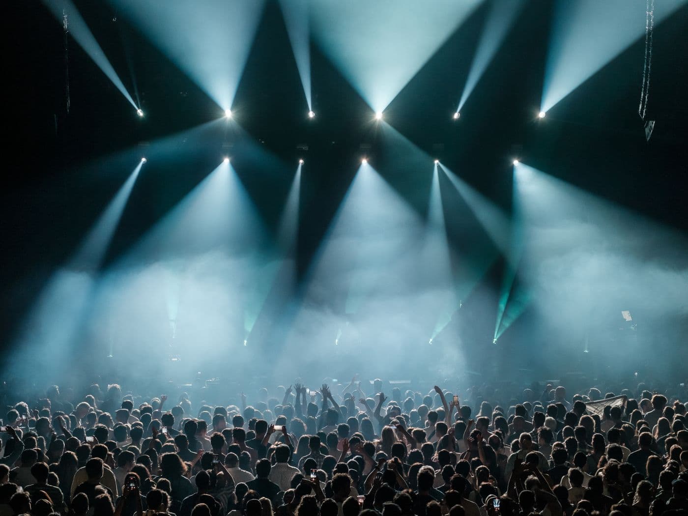 A euphoric festival crowd lit up in beams of stage light